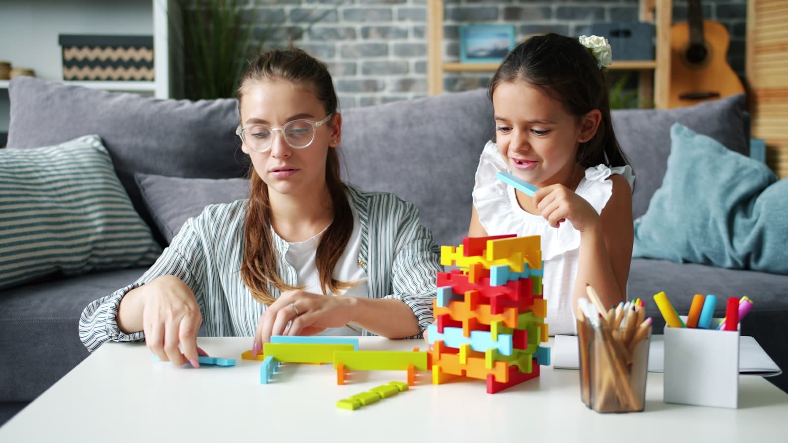 Two kids building together with colorful blocks at a table